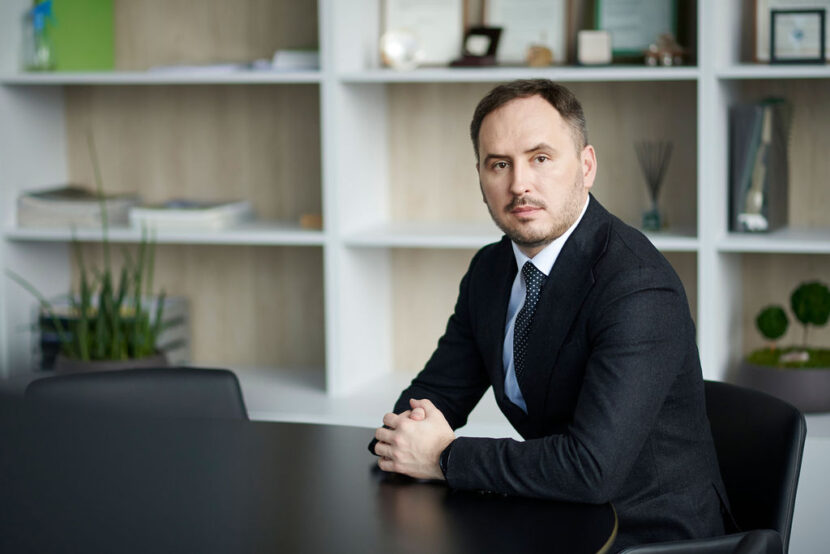 Lietuvos centrinės kredito unijos administracijos vadovas ir valdybos pirmininkas biuro aplinko sėdi prie stalo ir žvelgia į kamerą.